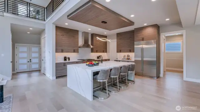 Enviable gourmet kitchen boasts 48" Subzero Refrigerator, Wolf Double-Oven, 6-Burners & Griddle Range, 48" Zephyr Pro Wall Hood, Sharp Microwave Drawer, and anchored by an oversized waterfall island.