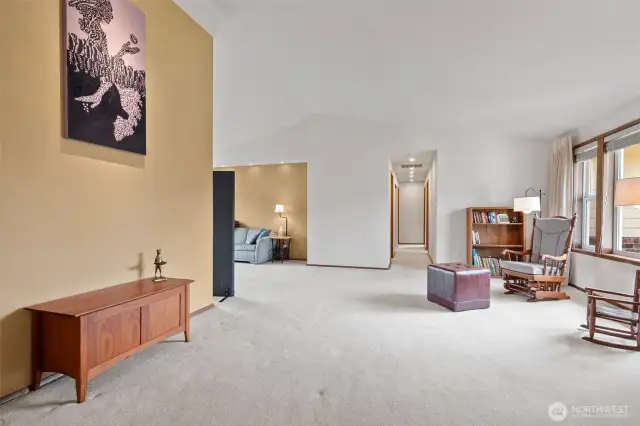 A view through from the double doors of the office/den across the entry into the living room showcasing some of this homes beautiful custom lighting.