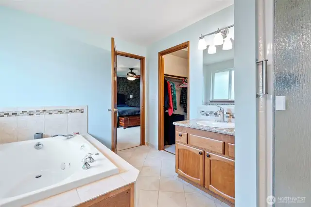 Another view of the primary bathroom showing the seperate shower and the entry to the walk in closet.