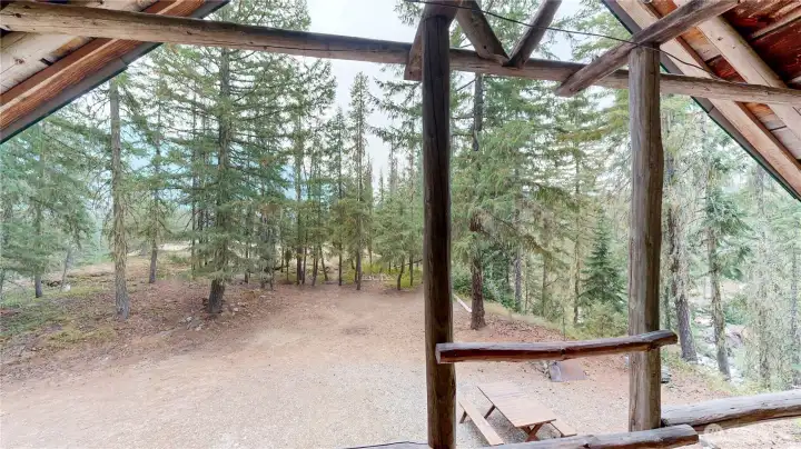 Private balcony with rustic log railing overlooking a wooded setting and natural landscape.