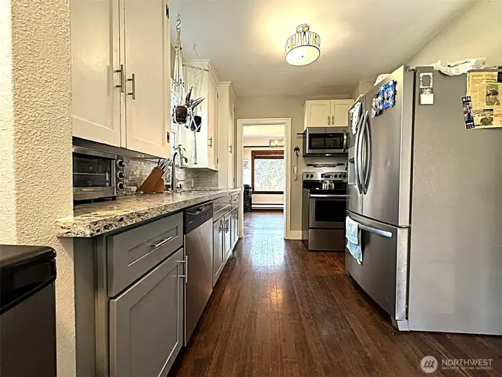 This photo showcases the recently updated kitchen, featuring modern stainless steel appliances and durable, elegant stone countertops, highlighting the quality and style of the remodel.