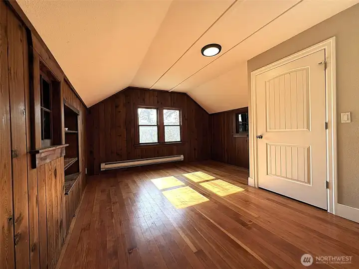 Upstairs bedroom 2 with hardwood floors, real wood wall coverings, and lots of natural light.