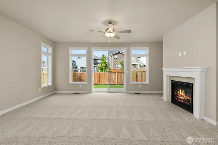 Living room with plenty of natural light featuring cozy gas fireplace with tile surround and ceiling fan.