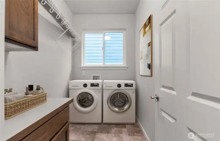 Separate laundry room with cabinets and a high hanging shelf for extended storage. Washer and Dryer will be included with this home. Virtually staged photo.