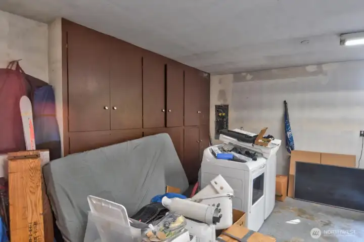 View if the storage area the attached garage. 2 cars are parked on the right. This is a deep garage. On the left of this picture is a door to the outside