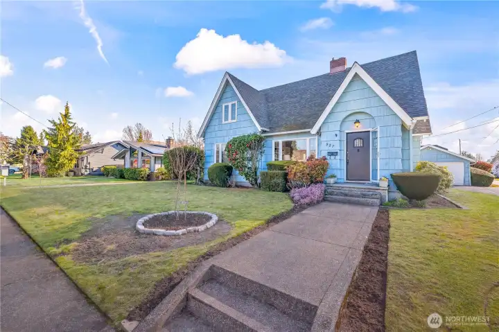 Front Exterior: This charming 1930s Tudor-style home boasts striking blue shake siding and iconic steep gables. The manicured lawn and classic arched entryway offer undeniable curb appeal in a peaceful neighborhood.