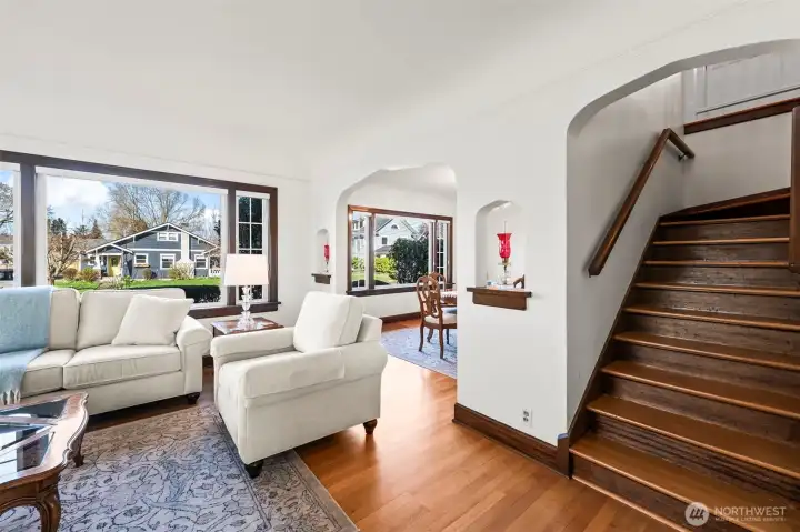 Staircase & Loft Access: The living area flows seamlessly toward a classic wooden staircase leading to the upper-level bedrooms and loft, highlighting the home's functional and open layout.