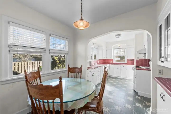 Charming Breakfast Nook: Adjoining the kitchen, this sunny breakfast nook features a classic pendant light and double windows. It’s an ideal spot for morning coffee, accented by the home's signature arched transitions.