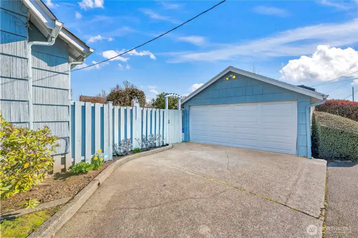 Detached Garage: The property includes a large detached two-car garage with matching blue siding and a wide concrete driveway, providing secure parking and additional storage options.