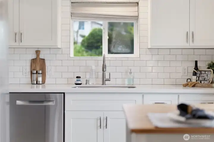 Updated kitchen with white cabinetry, stainless appliances, and window overlooking the yard.