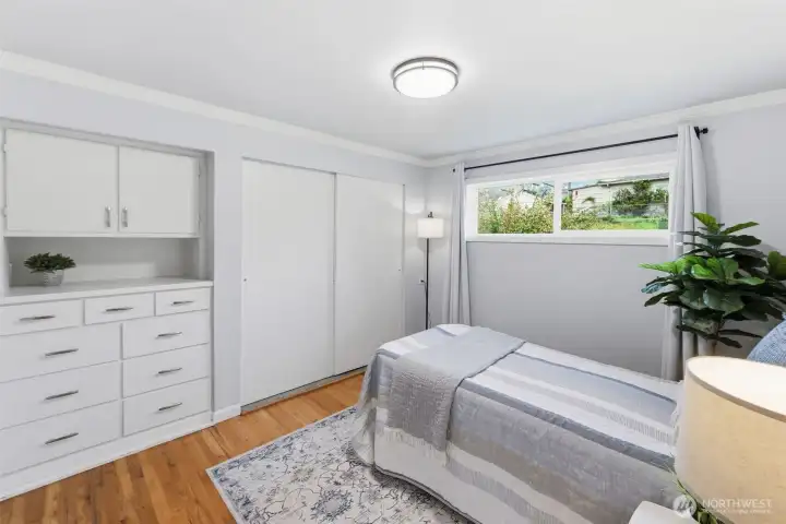 Spacious bedroom with built-in storage, large window, and functional layout.