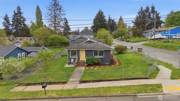 Front aerial view of Tacoma home featuring large yard, curb appeal, and corner lot presence.