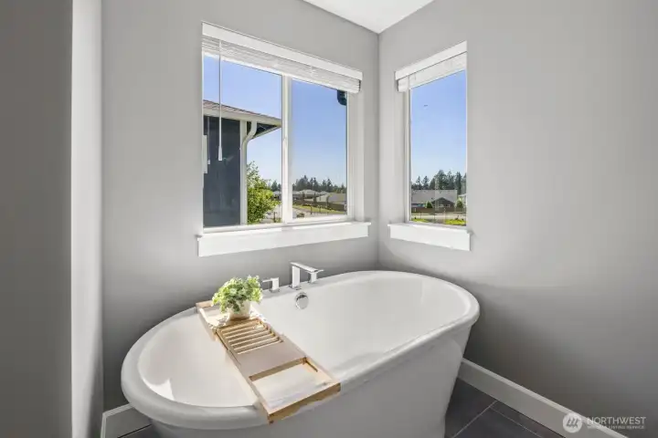 A freestanding soaking tub framed by natural light creates a peaceful retreat within the primary suite, offering a quiet place to relax at the end of the day. A freestanding soaking tub framed by natural light creates a peaceful retreat within the primary suite, offering a quiet place to relax at the end of the day.