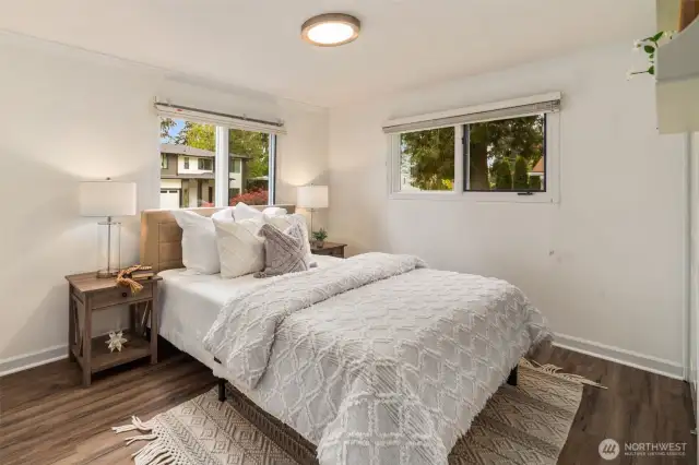 This is the first of three main-floor bedrooms, offering a convenient layout for guests or multi-generational living. Having at least one bedroom on the same level as the main living spaces provides easy access—ideal for older family members or anyone who prefers to avoid stairs. Large windows bring in natural light, complementing the soft wall tones for a bright and inviting atmosphere.