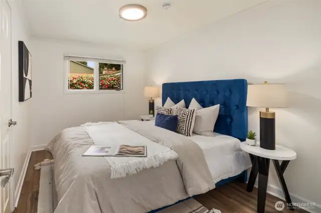 This is the second bedroom on the main floor, featuring crown molding, soft neutral tones, and warm lighting. A large window adds natural light, creating a cozy and inviting atmosphere.