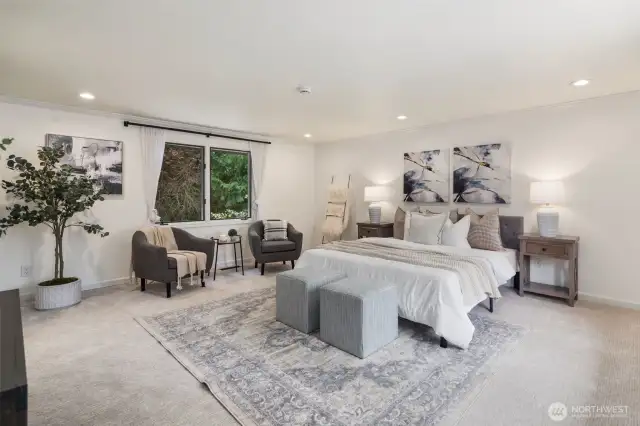 The top-floor primary suite offers a private retreat, occupying the entire level. Spacious and serene, the bedroom features soft carpeting, recessed lighting, and a cozy sitting area.