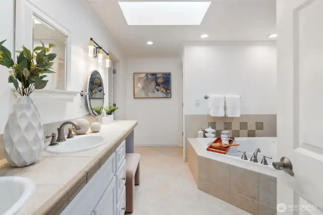 This generous ensuite bath features a dual-sink vanity with ample counter space and storage. A stylish oval mirror complements the updated lighting, while the dedicated makeup and hair station offers a perfect spot to get ready in comfort. The walk-in closet is just steps away for added convenience.