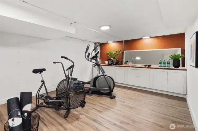 This adaptable basement room features a long counter with ample cabinetry underneath, providing an ideal setup for a home workshop or hobby space. The generous counter space and storage options make it perfect for DIY projects, crafts, or tool organization, catering to various creative or practical pursuits.