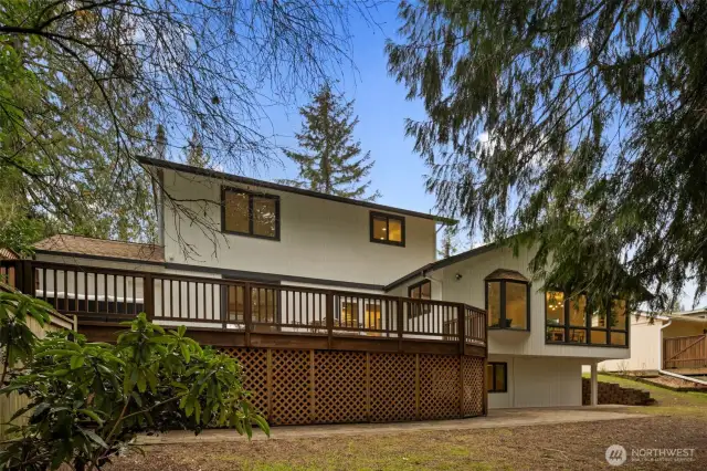 Enjoy the tranquility of the expansive deck offering a picturesque view of the lovely backyard framed by majestic cedar trees.