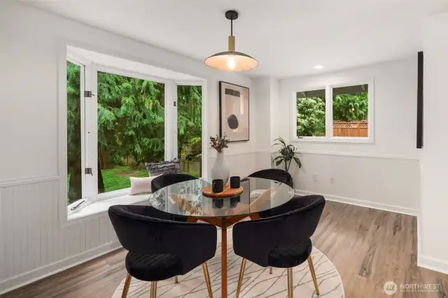 Natural light pours into this inviting dining nook, framed by a charming bay window with a built-in bench—perfect for cozy seating and book reading. The wainscoting detail adds charm, while the open layout provides an easy connection to the rest of the home. A wonderful spot to enjoy meals while overlooking the peaceful outdoor setting.