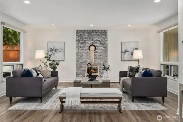 This expansive living room offers a perfect blend of comfort and style, featuring a cozy gas fireplace framed by a striking brick accent wall.