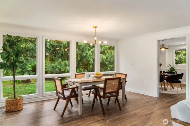 Expansive floor-to-ceiling windows flood the formal dining area with natural light and offer a seamless connection to the lush outdoor setting. A window on the adjacent wall will offer a cool cross breeze in the summertime. The modern chandelier adds a stylish touch, while the spacious layout is perfect for gatherings and special occasions.