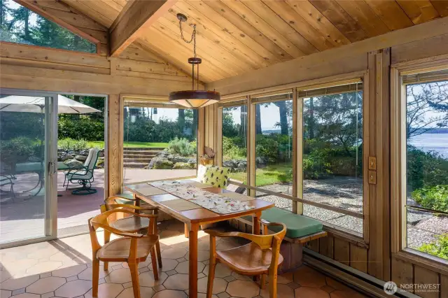 Walls of windows surround the dining area overlooking the patio, deck and beyond to the Channel.