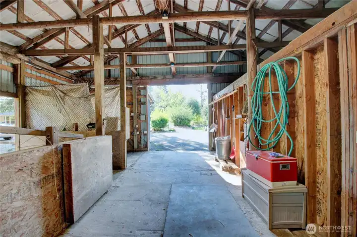 View of the barn interior main walkway.  Stalls are on the left and a door to right leads to a great area for equipment and tools.