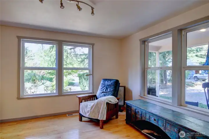 Living area with hardwood floors through-out, large double pane windows with views of the property.