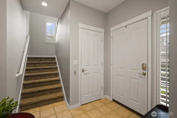 Staircase from tiled foyer with large closet under staircase.