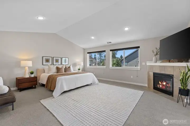 Expansive primary suite with vaulted ceilings, cozy gas fireplace, and large windows, offering a peaceful retreat within this Lynnwood home.