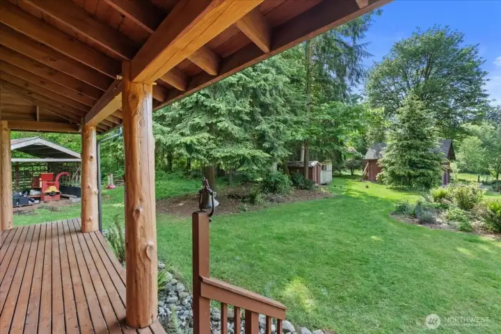 Covered wood porch with Japanese Joinery overlooking manicured lawn, mature landscaping, and detached outbuildings. Peaceful outdoor setting offers space for relaxing and enjoying the natural surroundings. Covered wood porch with Japanese Joinery overlooking manicured lawn, mature landscaping, and detached outbuildings. Peaceful outdoor setting offers space for relaxing and enjoying the natural surroundings.