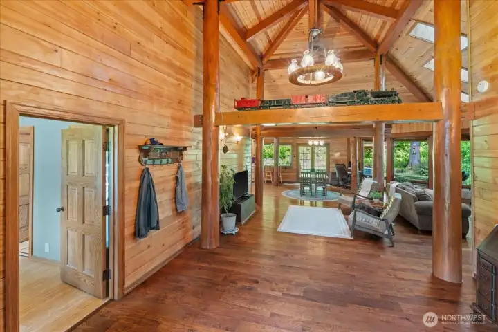 Expansive great room featuring vaulted wood ceilings, exposed timber posts and beams, hardwood flooring, and abundant natural light. Open-concept layout offers flexible living and entertaining space. Expansive great room featuring vaulted wood ceilings, exposed timber posts and beams, hardwood flooring, and abundant natural light. Open-concept layout offers flexible living and entertaining space.