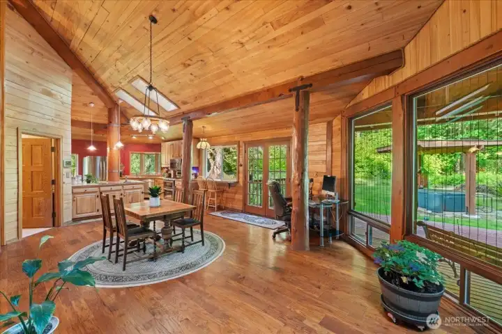Expansive great room featuring exposed timber-framed beams, soaring wood ceilings, and oversized windows overlooking the outdoor spaces. Open-concept layout connects the living, dining, and kitchen areas. Expansive great room featuring exposed timber-framed beams, soaring wood ceilings, and oversized windows overlooking the outdoor spaces. Open-concept layout connects the living, dining, and kitchen areas.