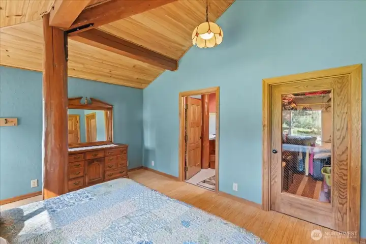 Primary bedroom featuring exposed wood beams, vaulted ceiling, and direct access to the adjoining bath area. Large closet and wood trim details add functionality and character. Primary bedroom featuring exposed wood beams, vaulted ceiling, and direct access to the adjoining bath area. Large closet and wood trim details add functionality and character.