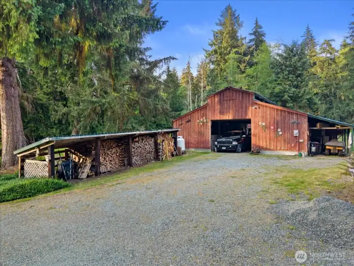 Large detached 36x36 barn or workshop building with covered wood storage area and gravel access. The structure offers ample space for equipment, storage, or workshop use. Large detached 36x36 barn or workshop building with covered wood storage area and gravel access. The structure offers ample space for equipment, storage, or workshop use.