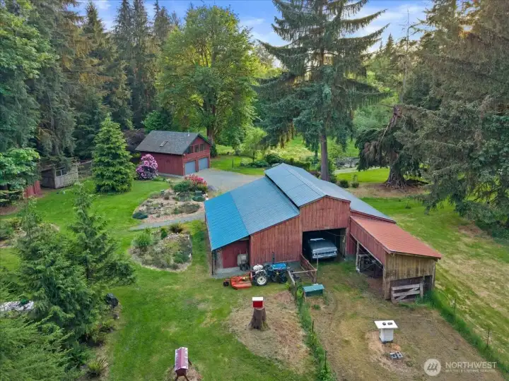 Aerial perspective highlighting the barn, detached outbuildings, landscaped pathways, and expansive grounds. Mature trees provide privacy throughout the property. Aerial perspective highlighting the barn, detached outbuildings, landscaped pathways, and expansive grounds. Mature trees provide privacy throughout the property.