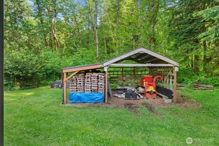 Covered storage structure offers additional space for equipment, tools, or firewood storage, surrounded by mature trees and open lawn areas. Covered storage structure offers additional space for equipment, tools, or firewood storage, surrounded by mature trees and open lawn areas.