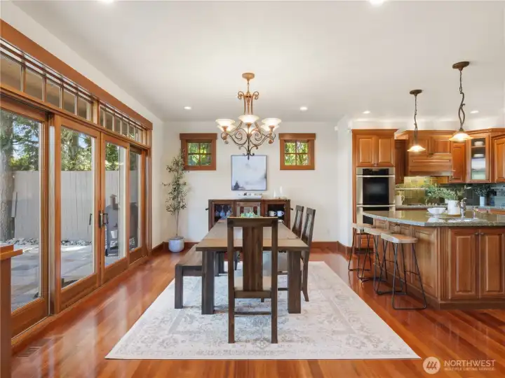 Bright dining space with hardwood floors, elegant lighting, and direct access to outdoor living areas through expansive glass doors. Bright dining space with hardwood floors, elegant lighting, and direct access to outdoor living areas through expansive glass doors.