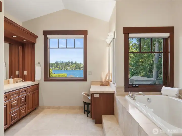 Enjoy water views from the comfort of the primary bath, featuring a soaking tub, dual-sink vanity, and abundant cabinetry. Enjoy water views from the comfort of the primary bath, featuring a soaking tub, dual-sink vanity, and abundant cabinetry.