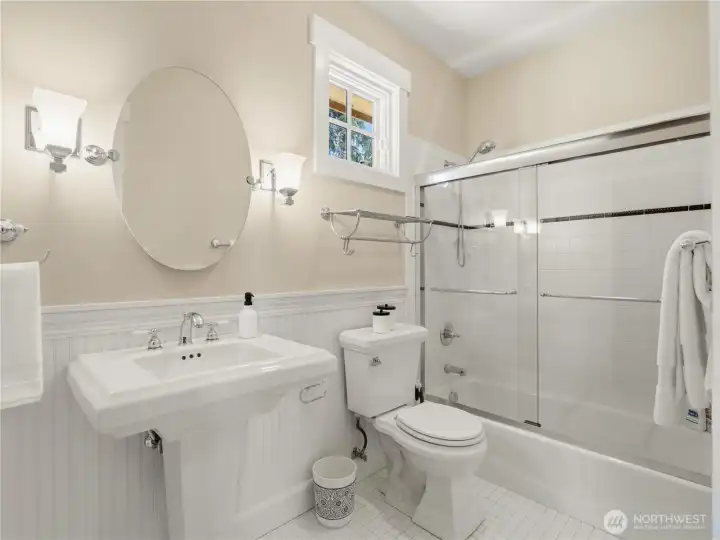 This well-appointed bathroom combines style and functionality with a glass-enclosed tub/shower, crisp tile finishes, and charming architectural details. This well-appointed bathroom combines style and functionality with a glass-enclosed tub/shower, crisp tile finishes, and charming architectural details.