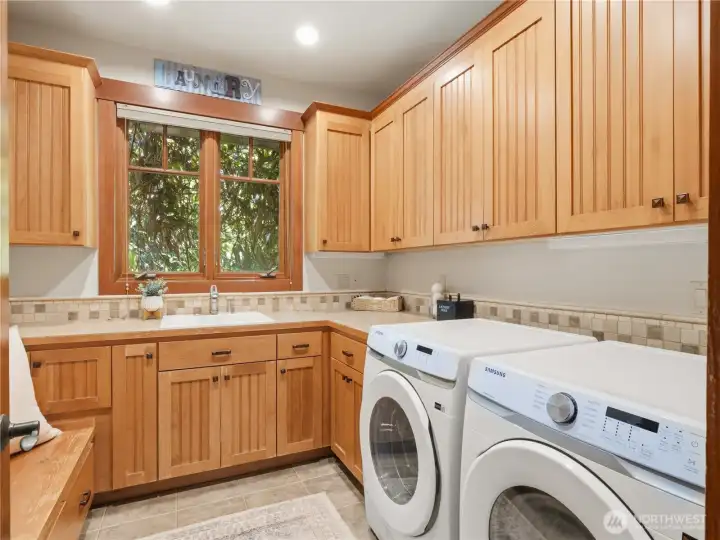 Spacious utility room featuring extensive custom cabinetry, generous counter space, utility sink, and dedicated laundry area. Spacious utility room featuring extensive custom cabinetry, generous counter space, utility sink, and dedicated laundry area.