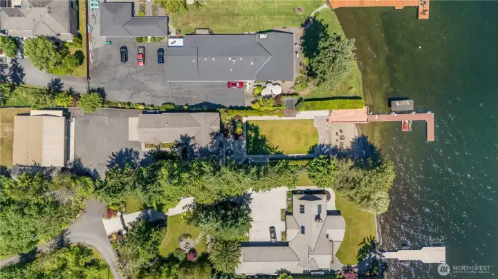An aerial view showcases the property's rare combination of private waterfront, expansive grounds, and a detached garage/shop offering exceptional flexibility for storage, recreation, and hobbies. An aerial view showcases the property's rare combination of private waterfront, expansive grounds, and a detached garage/shop offering exceptional flexibility for storage, recreation, and hobbies.
