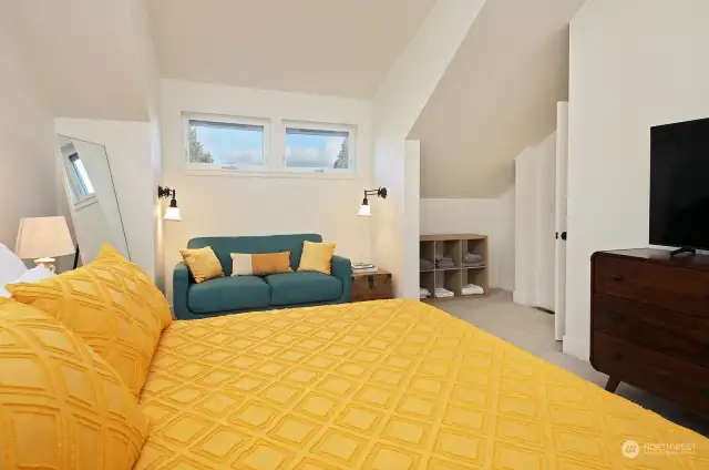 Looking back from where we were just standing. Dormers create a sweet place for a sofa or daybed. Another nook for storage as well.  Entrance/door to Primary is along the right edge of this photo near the shelving with towels.