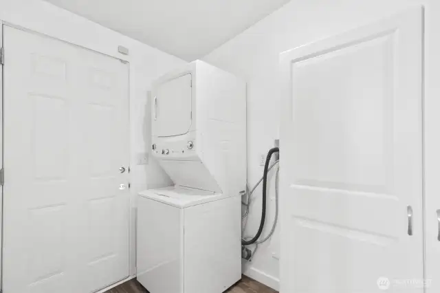 Laundry room with stack washer, dryer, storage closet and door to backyard