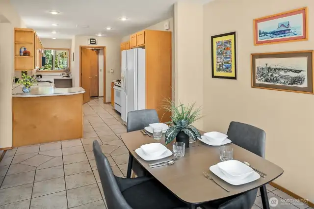 Bright light filled dining and kitchen with pantry, plenty of cabinetry and storage space. Door leads to utility room and 2 car garage.