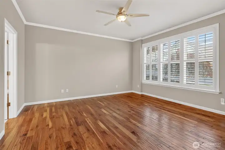 Main floor primary with wood floors and plantation shutters