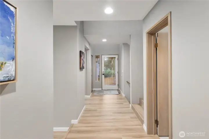 Clean, light-filled hallway with wide plank floors, recessed lighting, soft neutral tones, and a calm, contemporary flow throughout.