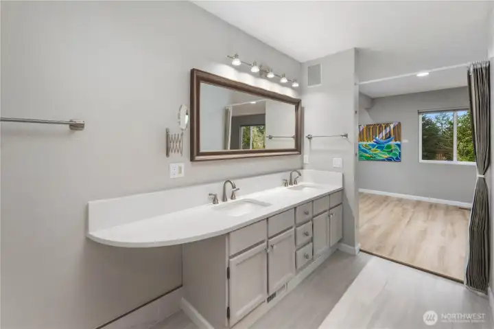 Bright primary bathroom with sleek vanity, framed mirror, modern lighting, and seamless transition to adjoining bedroom retreat.