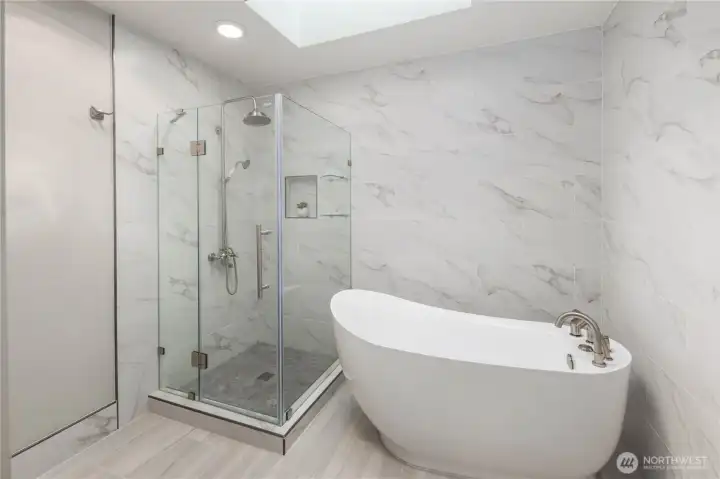 Spa-inspired bathroom showcases freestanding soaking tub, frameless glass shower, marble finishes, soft lighting, and serene modern design with elegant simplicity.